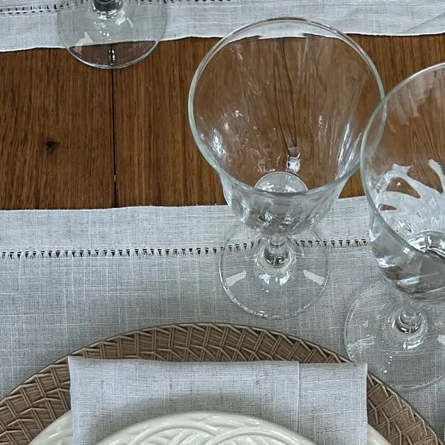 Close de taças de cristal sobre sousplat de palha e linho